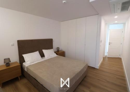 a bedroom with a large bed and a white wall at MyStay - Quinta das Aromáticas in Malta