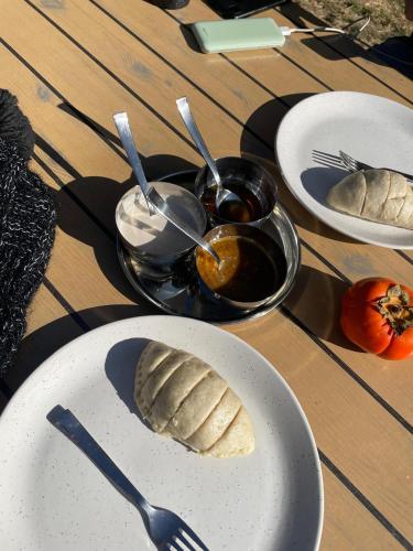 a table topped with plates of food with spoons and bread at Little Forest Homestay in Gushaini