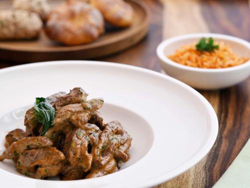 a plate of food with meat and a bowl of sauce at Mövenpick Hotel & Apartments Ghala Muscat in Muscat