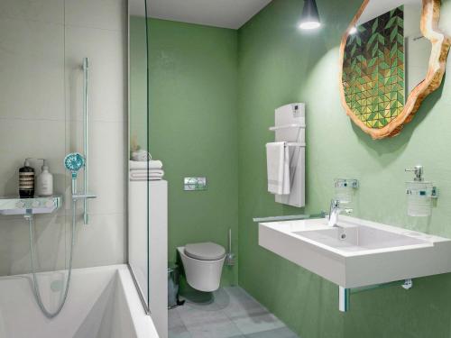 a green bathroom with a sink and a toilet at ibis Styles Bezons Paris La Défense in Bezons