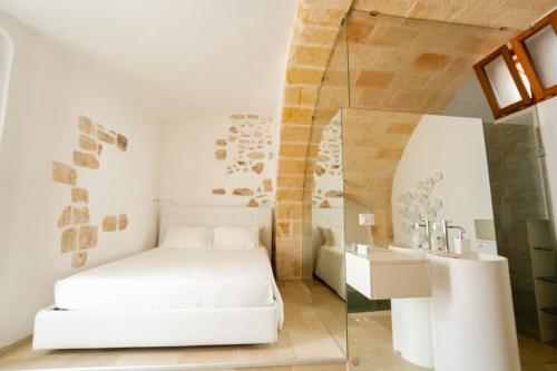 a bedroom with a white bed and a glass wall at Il Fico Luxury Suite & SPA in Polignano a Mare