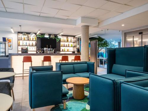 a lobby with blue chairs and a bar at ibis Styles Bezons Paris La Défense in Bezons