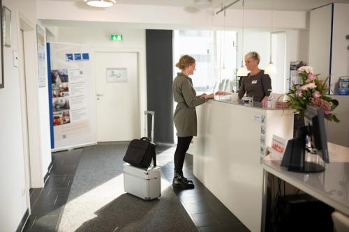 two people standing at a counter in an office at Hotel im Kornspeicher in Marburg an der Lahn