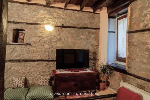 a living room with a tv on a stone wall at Villa Norma in Órma