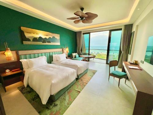 a bedroom with a bed and a room with a view at Angsana Quan Lan, Ha Long Bay in Quan Lạn