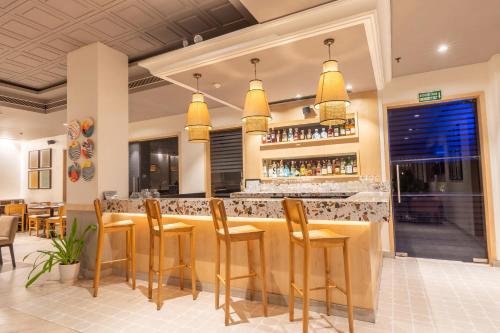 a restaurant with a bar with yellow stools at Park Inn by Radisson,South Delhi in New Delhi