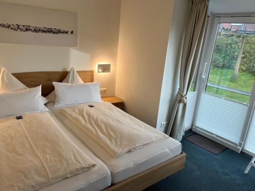 two beds in a room with a window at Sander's Höft Appartments - Direkt am Strandaufgang in Juist