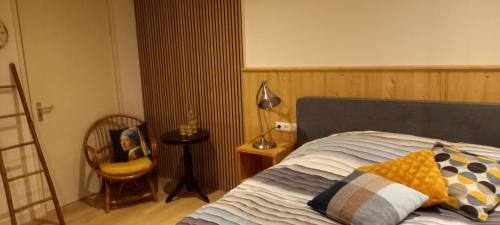 a bedroom with a bed and a chair and a lamp at B&B Stations Koffiehuis in Molkwerum