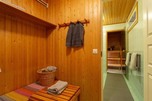 La salle de bains est pourvue d'un mur en bois avec un banc et des serviettes. dans l'établissement Villa Arctic Harmony near SCV, à Rovaniemi