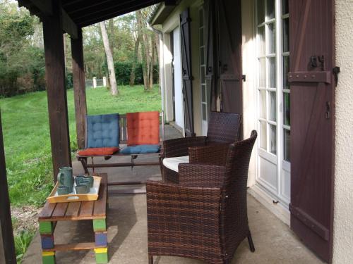 a porch with wicker chairs and a bench on it at Cantebos - Maison avec 3800 m² de jardin in Saint-Laurent-de-Médoc