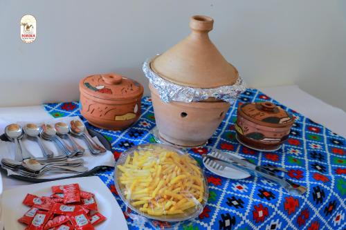 a table topped with a plate of pasta and a vase at DoroKa Nubian House in Aswan