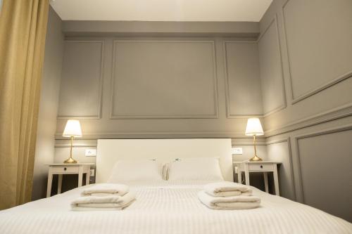a bedroom with a white bed with towels on it at Lovcevic Apartmani & Sobe in Šabac