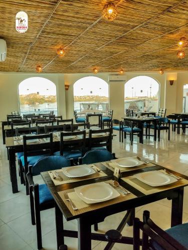 a restaurant with wooden tables and chairs and windows at DoroKa Nubian House in Aswan