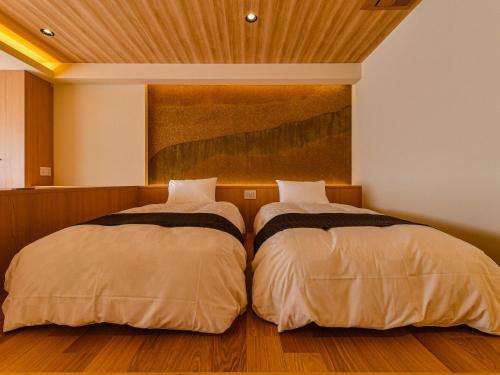 two beds sitting next to each other in a bedroom at Hokuriku Fukui Awara Onsen Mimatsu in Awara