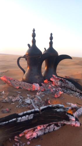 a teapot sitting on the ground in the desert at Sama Al Sharqiyah Camp in Al Wāşil
