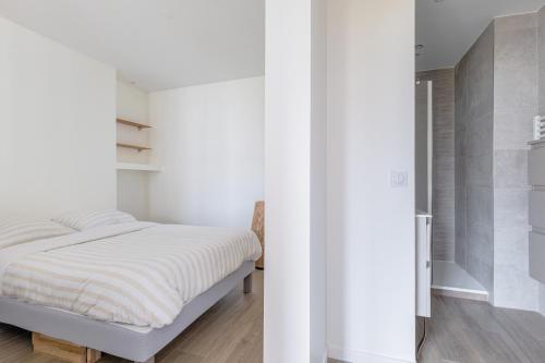 - une chambre avec des murs blancs et un lit blanc dans l'établissement LE LAC - Appartement 15' Partdieu et Bellecour, à Lyon
