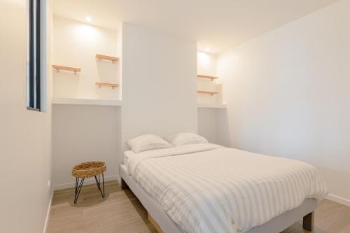 - une chambre blanche avec un lit et un tabouret dans l'établissement LE LAC - Appartement 15' Partdieu et Bellecour, à Lyon