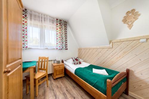 a bedroom with a bed and a table and a chair at Willa Górski Potok - W CENIE ŚNIADANIE I ZNIŻKI NA TERMY ! in Biały Dunajec