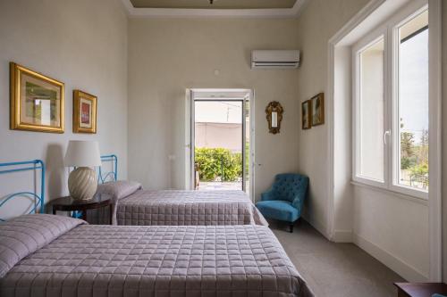 a bedroom with two beds and a chair and a window at 4 Bedroom Villa, Private Pool, Marsala in Marsala