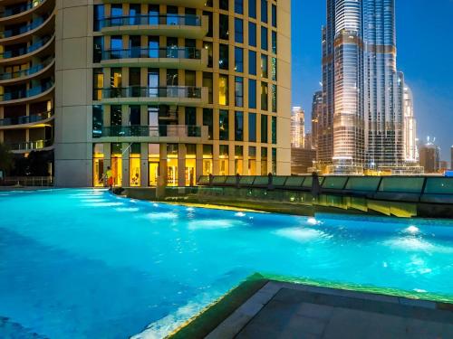 a swimming pool with a city skyline in the background at Vacay Lettings - High floor Burj Khalifa & Fountain view 3 bed in Dubai