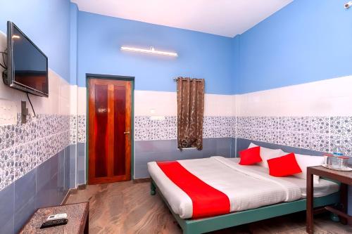 a bedroom with a bed with red pillows and a tv at AURO GUEST HOUSE in Auroville
