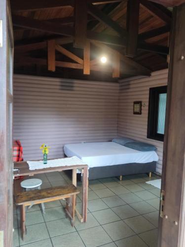 a small room with a bed and a table at Cabana na Montanha in Morretes