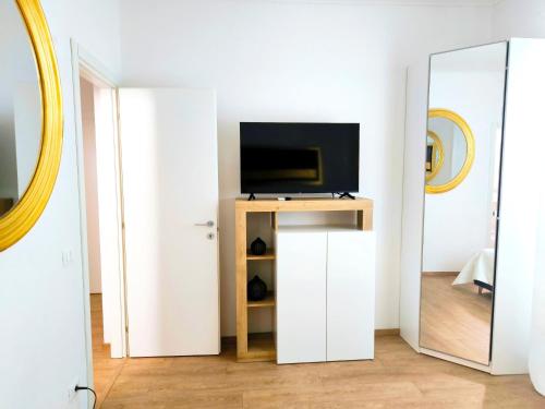 a living room with a tv and a mirror at Appartamento "Laghetto 1" con tre camere e bagni privati cucina in condivisione in Castel San Pietro Terme