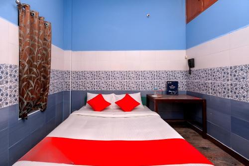 a small room with a bed with red pillows at AURO GUEST HOUSE in Auroville