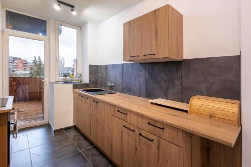 a kitchen with wooden cabinets and a large window at NOMAD APARTMENTS - Henin in Charleroi