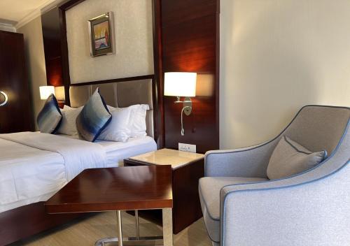 a hotel room with two beds and a chair at Grand Palace Hotel Lusaka in Lusaka