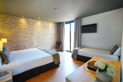 a hotel room with two beds and a brick wall at Arc La Rambla in Barcelona