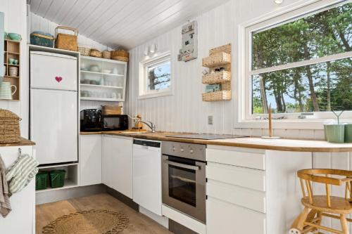 a kitchen with white cabinets and a sink and a window at Rødby, Bredfjed nær Lalandia in Rødby
