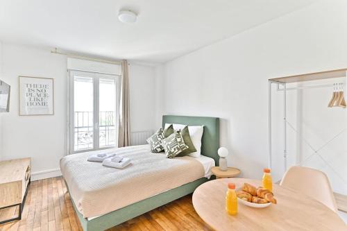 une chambre blanche avec un lit et une table dans l'établissement Agréable studio dans la paisbile de Montreuil-II, à Montreuil