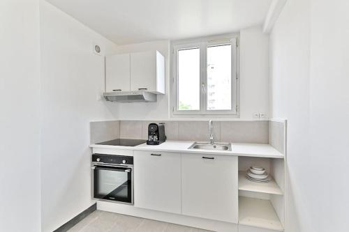 une cuisine blanche avec un évier et une cuisinière dans l'établissement Agréable studio dans la paisbile de Montreuil-II, à Montreuil