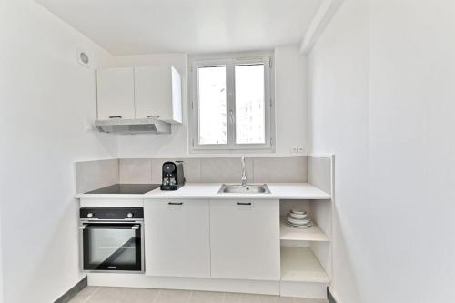 une cuisine blanche avec un évier et une fenêtre dans l'établissement Agréable studio dans la paisbile de Montreuil-II, à Montreuil