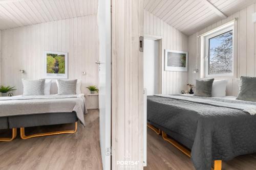 two beds in a white room with two windows at Ferienhaus Bergkristall - Sankt Andreasberg im Harz in Sankt Andreasberg