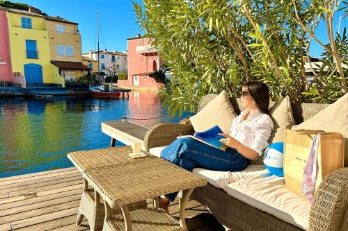 une femme assise sur un canapé en train de lire un livre dans l'établissement Renovated house with WIFI AC a large terrace and a mooring, à Grimaud