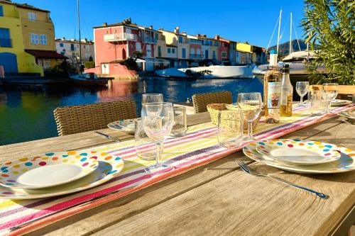 une table en bois avec des assiettes et des verres à vin dessus dans l'établissement Renovated house with WIFI AC a large terrace and a mooring, à Grimaud