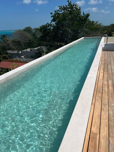 a swimming pool with a wooden deck and the ocean at MICAELA apartment pool AC next to the lagoon in Bacalar