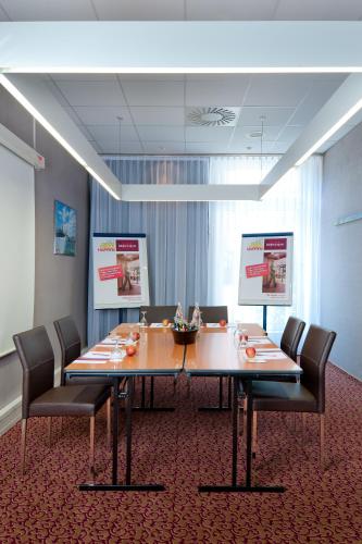 a conference room with a large wooden table and chairs at Mercure Hotel Hamburg am Volkspark in Hamburg