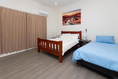 a bedroom with two beds and a window with curtains at Glenelg North House, 3QBed, 2KSBed, 2Bth, 5TV in Glenelg