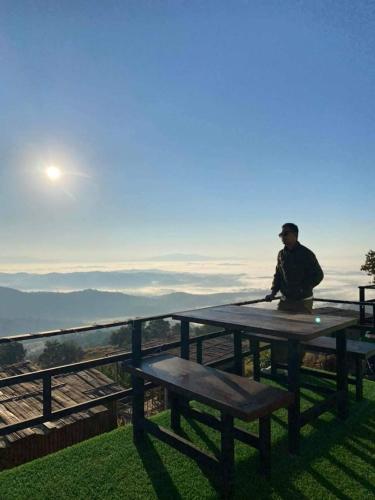 a man sitting at a picnic table with a view at ดอยสะโง้วิวโฮมสเตย์โดมบอล in Chiang Saen