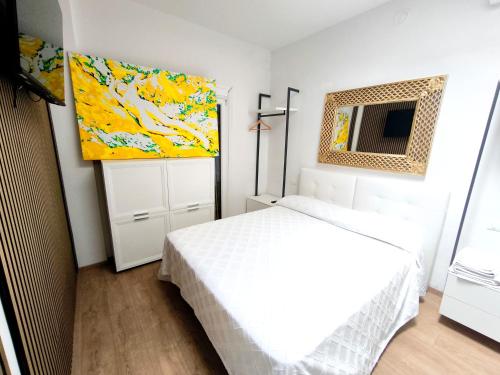 a bedroom with a white bed and a painting on the wall at Appartamento "Laghetto 1" con tre camere e bagni privati cucina in condivisione in Castel San Pietro Terme