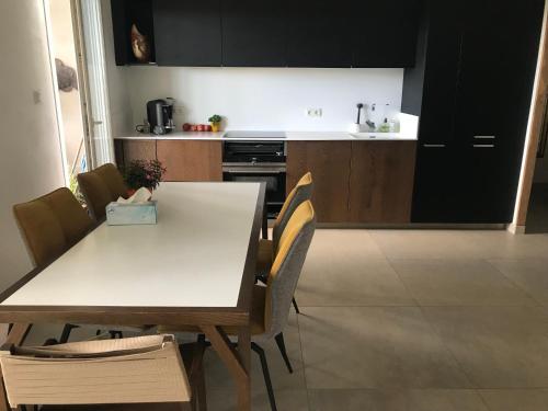 - une cuisine avec une table et des chaises blanches dans la chambre dans l'établissement Appartement parc Marianne espace fitness, à Montpellier