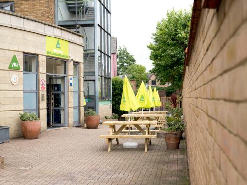 two picnic tables with yellow umbrellas in front of a building at YHA London Thameside in London