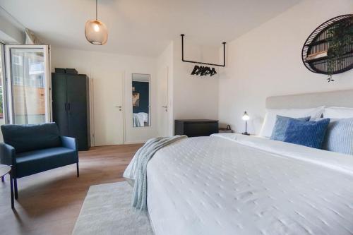 a bedroom with a large white bed and a chair at Citycenter Living 1Zi HP 2P Mitte in Bremerhaven