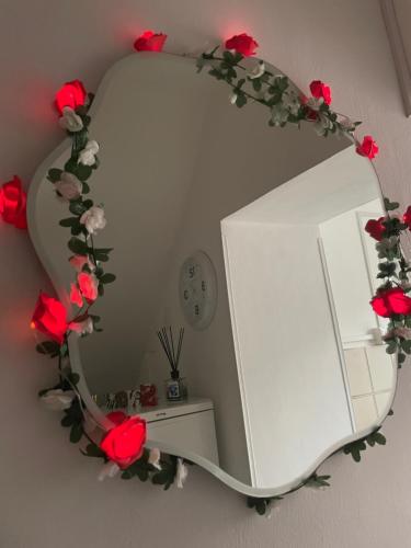 a round mirror with red roses on a wall at Sweet Home Sofia in Norma