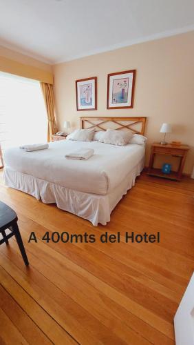 a bedroom with a large white bed with a wooden floor at Hotel y Cabañas Llanuras de Diana - Caja Los Andes in Puerto Natales