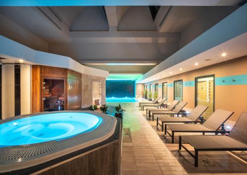 a large room with a hot tub and lounge chairs at Hotel Spa Le Pasino in Le Havre