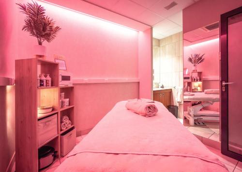 a pink room with a large bed in it at Hotel Spa Le Pasino in Le Havre